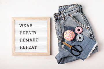 Jeans with letter board and text wear, repair, remake, repeat. Slow fashion, circular economy, eco friendly sustainable shopping, thrifting second hand shop concept. - obrazy, fototapety, plakaty