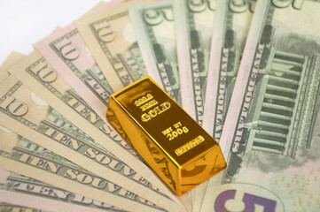 Gold bar and American dollars banknotes Banknotes are fanned out and covered with a gold bar. invest in precious metals and save money