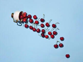 Fresh cherries and coffee cup isolated against pastel blue background. Creative nature concept....