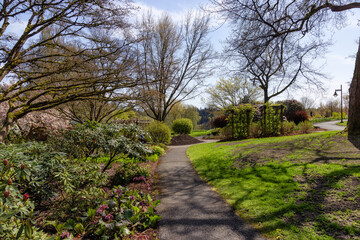 Path in a green vibrant garden with colorful flowers in a modern city park. Deer Lake, Burnaby, Vancouver, British Columbia, Canada.