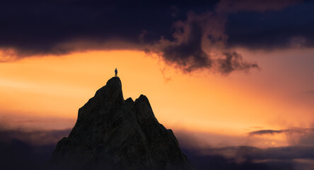 Adventurous Man Hiker Standing on top of a rocky mountain overlooking the dramatic landscape at sunset. 3d rendering peak. Background dramatic Cloudscape. Adventure Concept Artwork