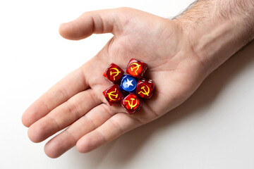 One cube with the symbol star surrounded by five cubes with the symbol hammer and sickle are on a man's palm. The concept of the ideology of communism and capitalism.