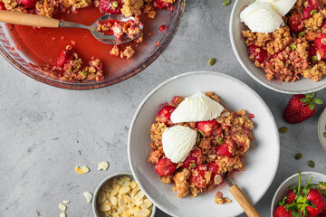 Tasty breakfast. Strawberry crumble with ice cream, almonds and pumpkin seeds in a plate on gray background. top view