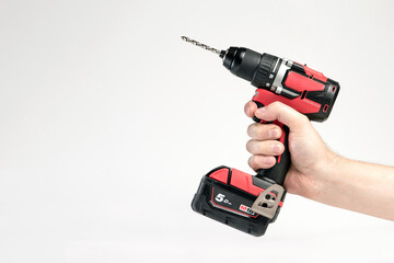 Cordless drill in black and red. Screwdriver with a drill in hand on a white background. Modern carpentry tool.