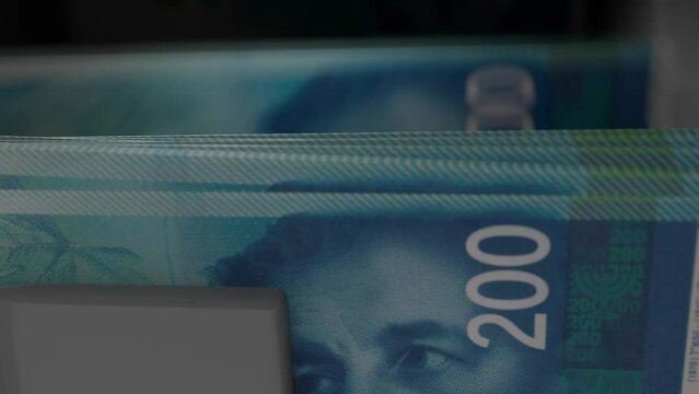 200 Israeli shekels in cash dispenser. Withdrawal of cash from an ATM. Financial transaction in the bank terminal. ILS.