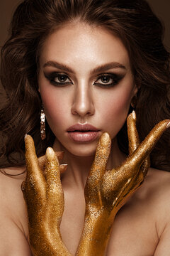 Beautiful girl with bright fashionable make-up and gold hands and accessories. Beauty face.