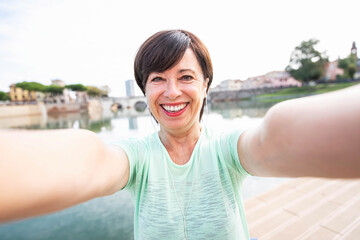 Senior woman taking a selfie portrait doing fitness outdoors - Mature woman doing jogging at the park -Senior people and fitness concept.