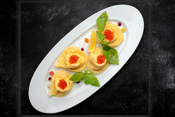 Pancakes with red caviar, basil, dark background