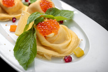 Pancakes with red caviar, basil, dark background