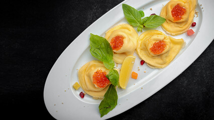 Pancakes with red caviar, basil, dark background