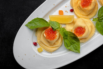 Pancakes with red caviar, basil, dark background