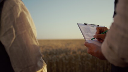 Partners signing contract wheat field. Farmers hands hold clipboard close up.