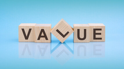 Value - word is written on wooden cubes on a bright blue background. close-up of wooden elements