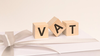 three cubes with text vat on the white surface of a gift box tied with a light festive ribbon