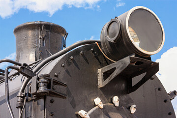 View of the front of the old steam locomotive with the smokestack, headlight and smokebox door close-up