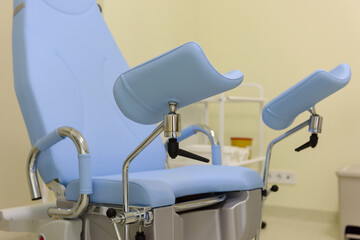 Gynecological chair in a modern gynecologist's office. Empty gynecological bed in the obstetrics and gynecology department. Clinic or hospital interior. Modern medical equipment and tools close-up.