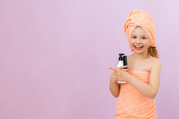 A little girl is going to spread cream on her body after a shower. children's body hygiene, a joyful child with a towel on his head.