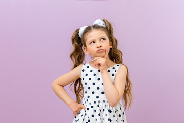 A thoughtful little girl looks up. a child in a dress on an isolated background.