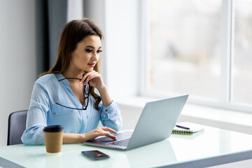 Young woman smiling while working with laptop in office
