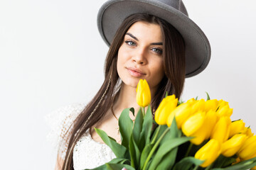 Young woman with bouquet of yellow tulips on white background