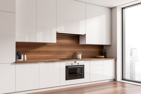 Light kitchen interior with kitchenware and appliances, panoramic window