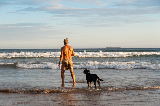 Man enjoying on the beach with his dog at sunset, Buzios, Brasil.