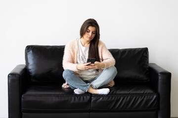 Portrait beautiful young woman use smart mobile phone on sofa in living room interior