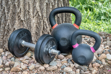 heavy dumbbell and iron kettlebells in backyard, home fitness concept