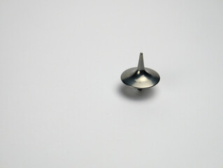 Silver spinning top rotating on a seamless white background