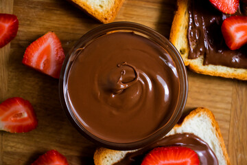 Toasted bread with chocolate spread strawberries on a wooden background