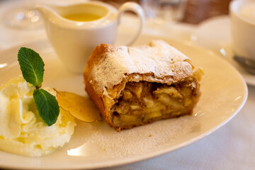 Austrian sweet dessert, portion of apple strudel with whippen cream and hot vanilla sauce served in old bakery cafe in Vienna, Austria