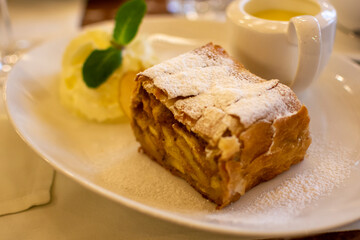 Austrian sweet dessert, portion of apple strudel with whippen cream and hot vanilla sauce served in old bakery cafe in Vienna, Austria