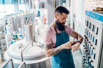 Men working at brewery and using a smartwatch application for fermentation process