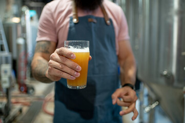 Close shot of a man holding glass of beer in brewery