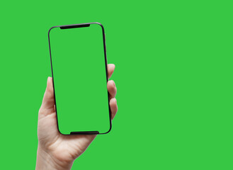 A woman's hand holds a smartphone with a blank screen and a modern frameless design on a green...