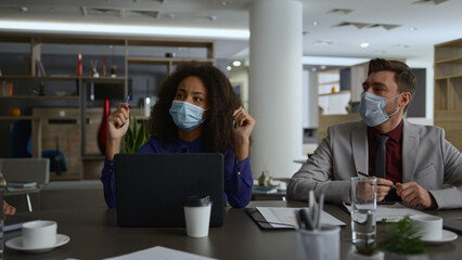 Business team wearing masks discuss corporate strategy in coronavirus pandemic.