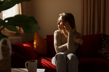 Lady lying touching temples.Young woman suffering headache, migraine, depression, sitting on sofa, home interior.