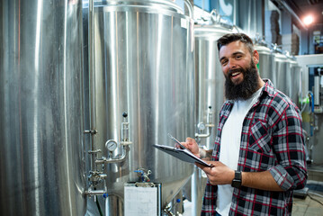 Man working in brewery and taking notes of the beer production