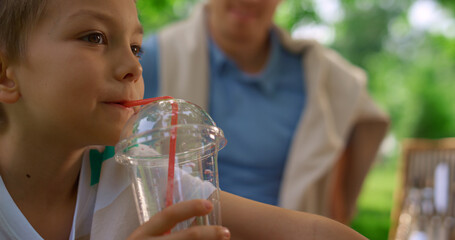 Cute boy drink juice with strow close up. Cheerful child taste fresh beverage.