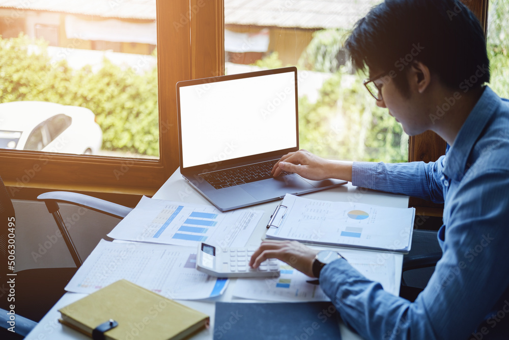 Poster a business man using blank white screen computer laptop with a calculator to calculate budget docume
