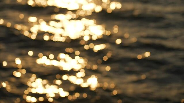 Slow motion blurry defocused stock 4k video footage of beautiful wavy peaceful golden sunset sea water during dawn time. Aerial view. Natural abstract sunny video background. Christmas, Xmas backdrop