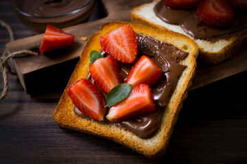 Toasted bread with chocolate spread strawberries on a wooden background
