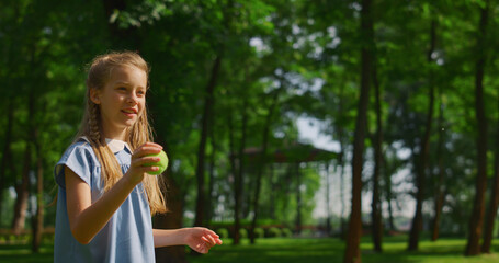 Girl training to throw ball in green park close up. Happy kid play outdoors.