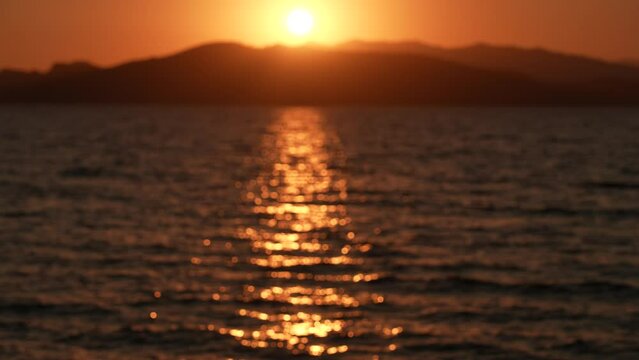 Beautiful defocused golden sunset marine landscape 4k video background. Amazing slow motion panoramic view of evening peaceful wavy surface of sea water, black silhouettes of mountains, sun circle