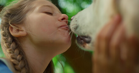 Portrait of chewing girl caressing dog closeup. Pet lick cute face on picnic. - obrazy, fototapety, plakaty