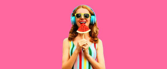 Summer colorful portrait of cheerful happy smiling young woman model posing in headphones listening to music with juicy slice of watermelon on pink background, blank copy space for advertising text