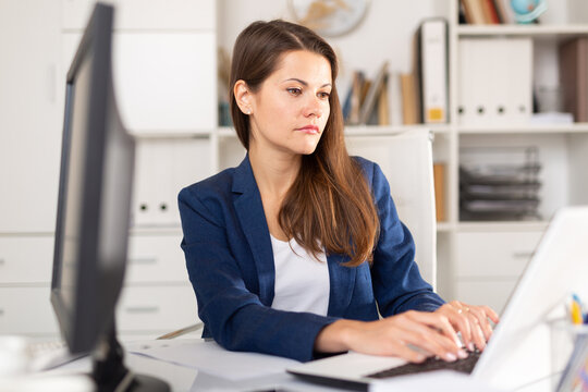 Smiling woman working with papers and laptop in office