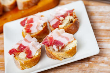 Appetizing sandwiches with salted bacon and horseradish on a plate. Close-up image