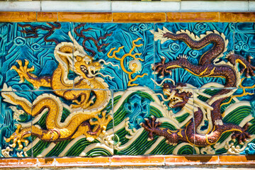Ancient Chinese art, colorful figures of fighting dragons on relief tiles.