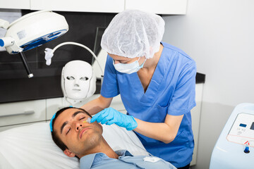 Portrait of male patient during cosmetology procedure in beauty clinic, getting carbon dioxide...